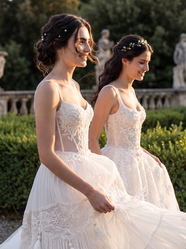Two models in white lace wedding gowns with full tulle skirts, seen in profile in a garden. AI-generated image.